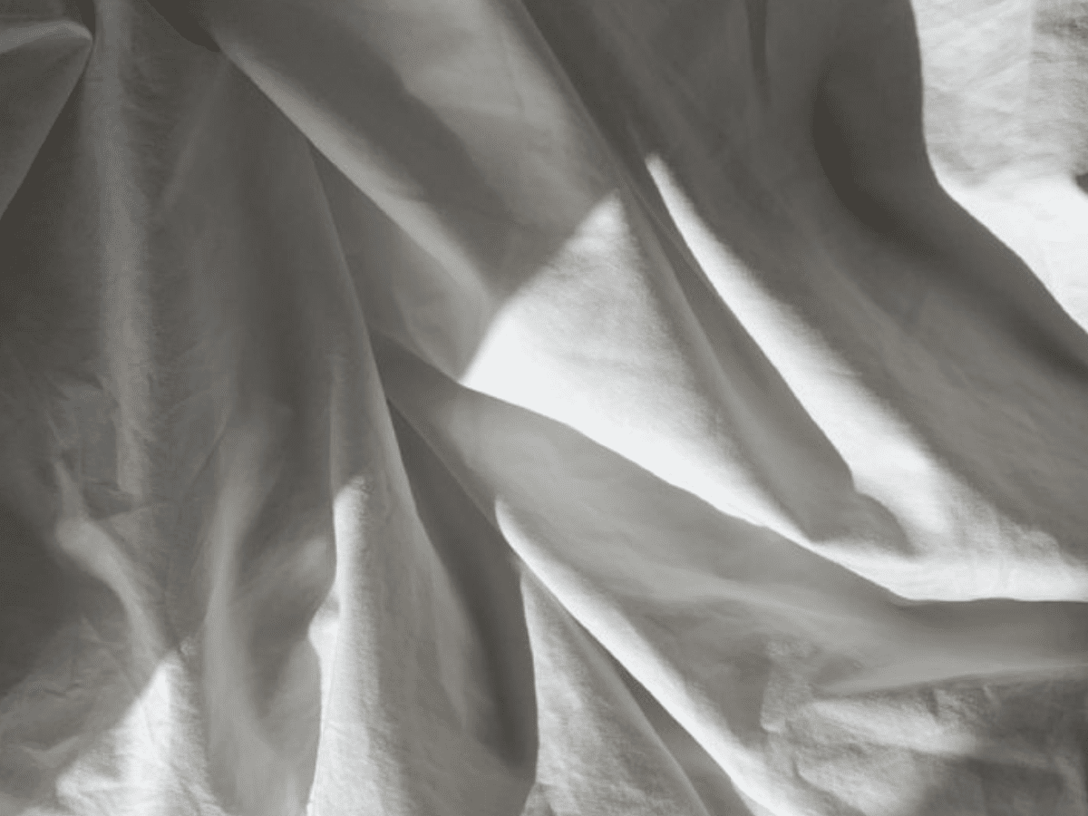 Crumpled silk sheets in soft light, symbolizing the sacred stillness and beauty of deep rest.
